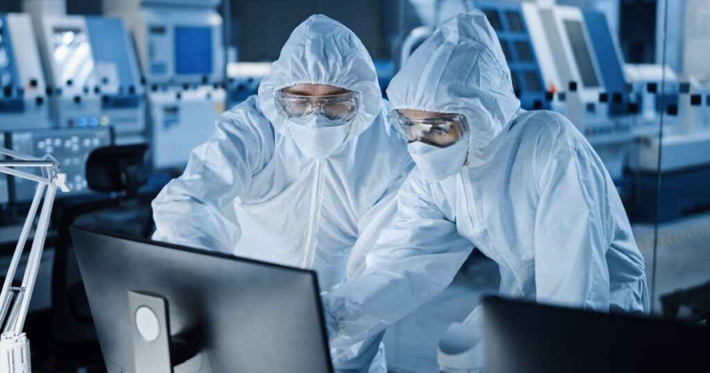 Two heavy industry manufacturing workers in cleanroom jumpsuits deciding between custom or standard seals
